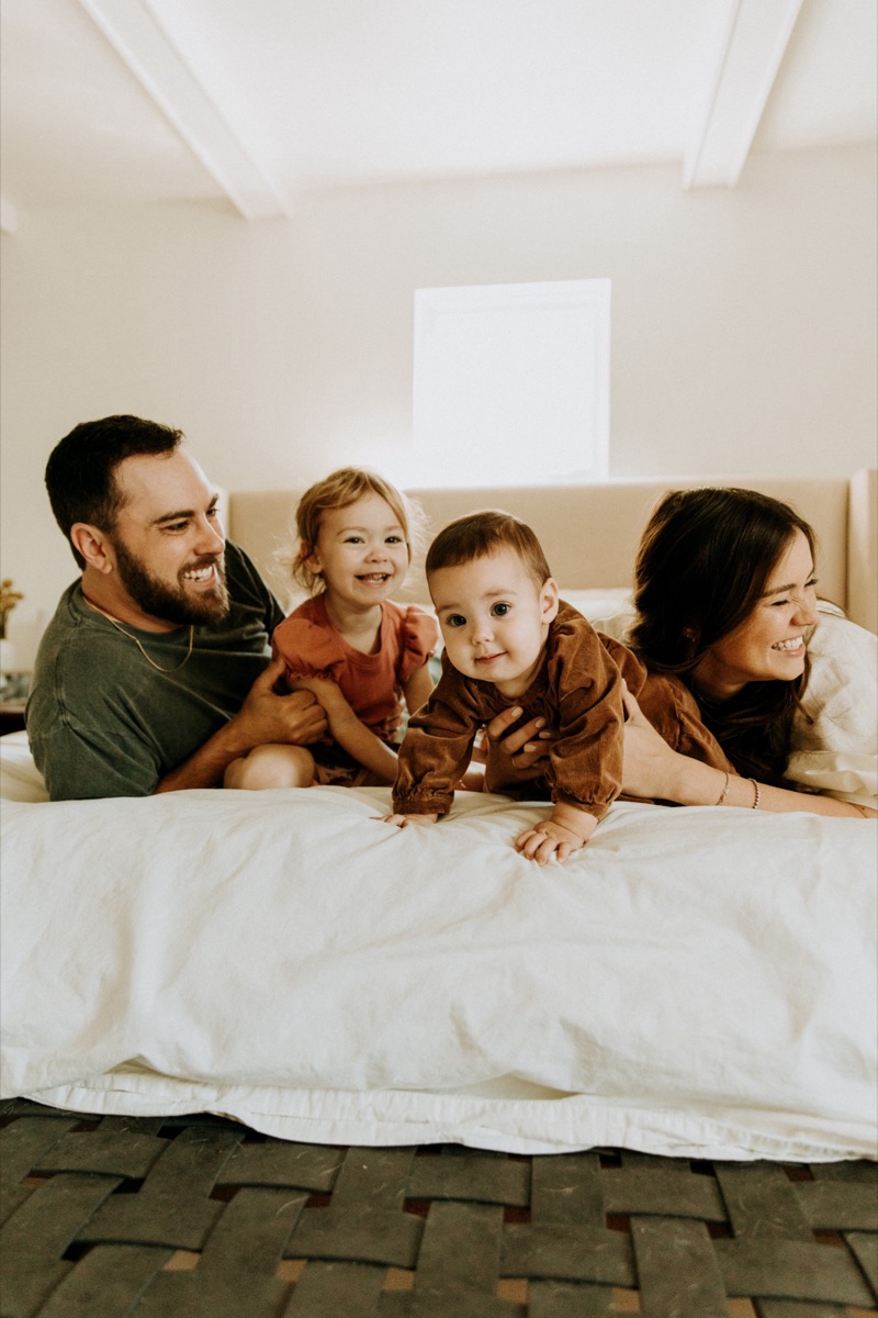 Aaron, his wife and daughters laughing on the bed