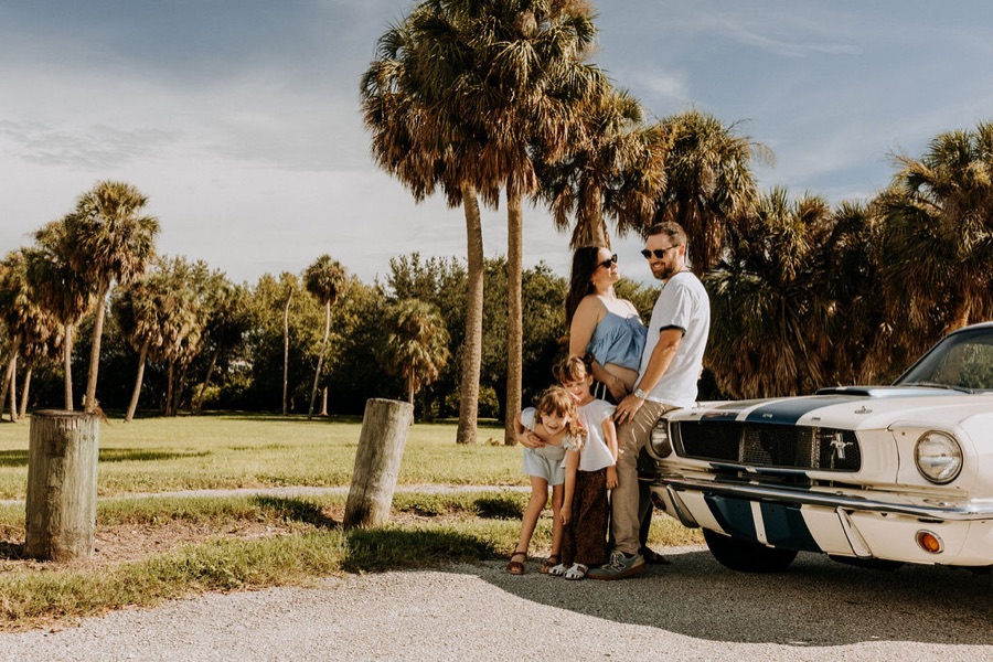 Aaron with his wife and daughters by a vintage Mustang