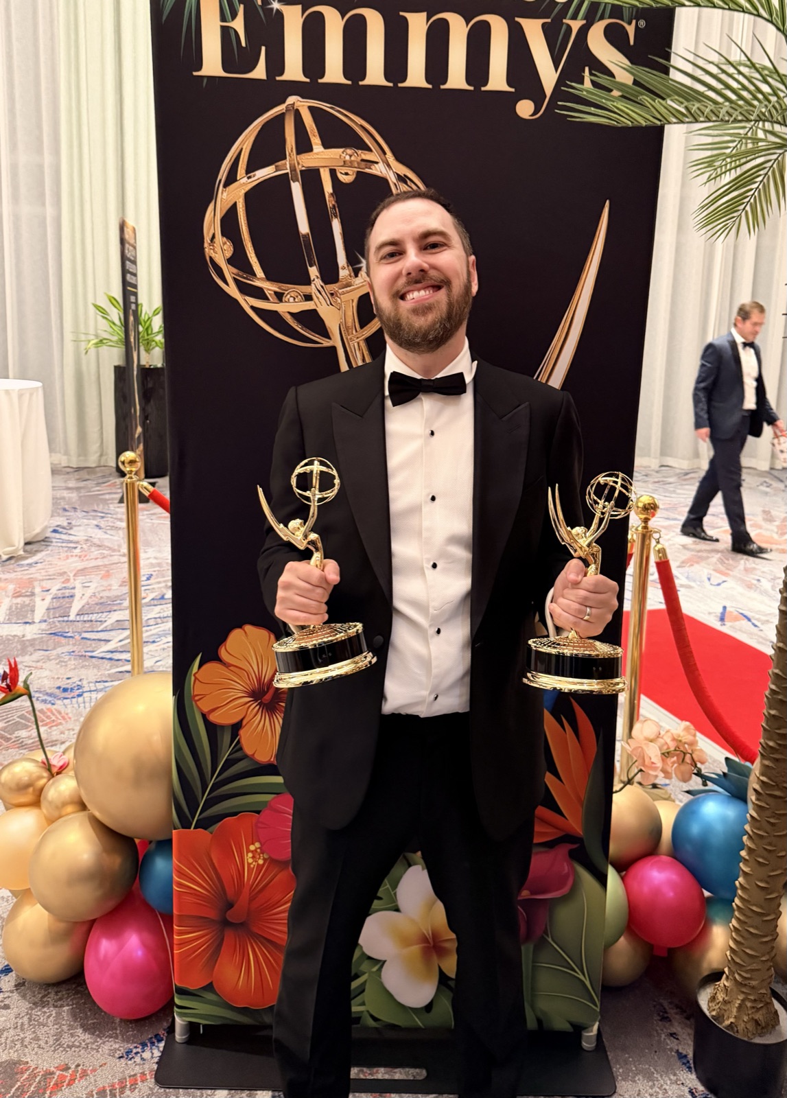 Aaron White holding two Emmy awards